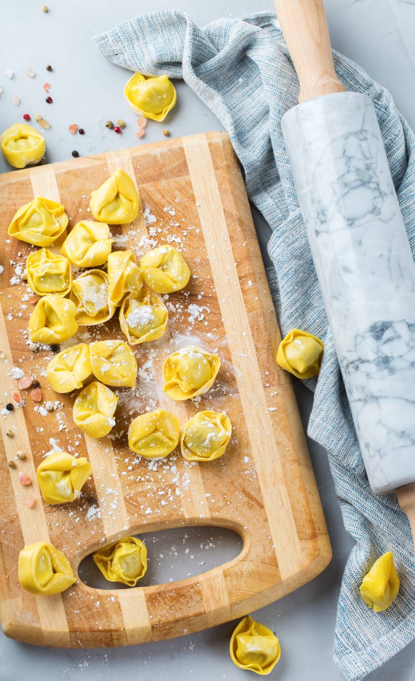 Selbstgemachte ungekochte Tortellini auf einem Holzbrett Selbstgemachte ungekochte Tortellini auf einem Holzbrett