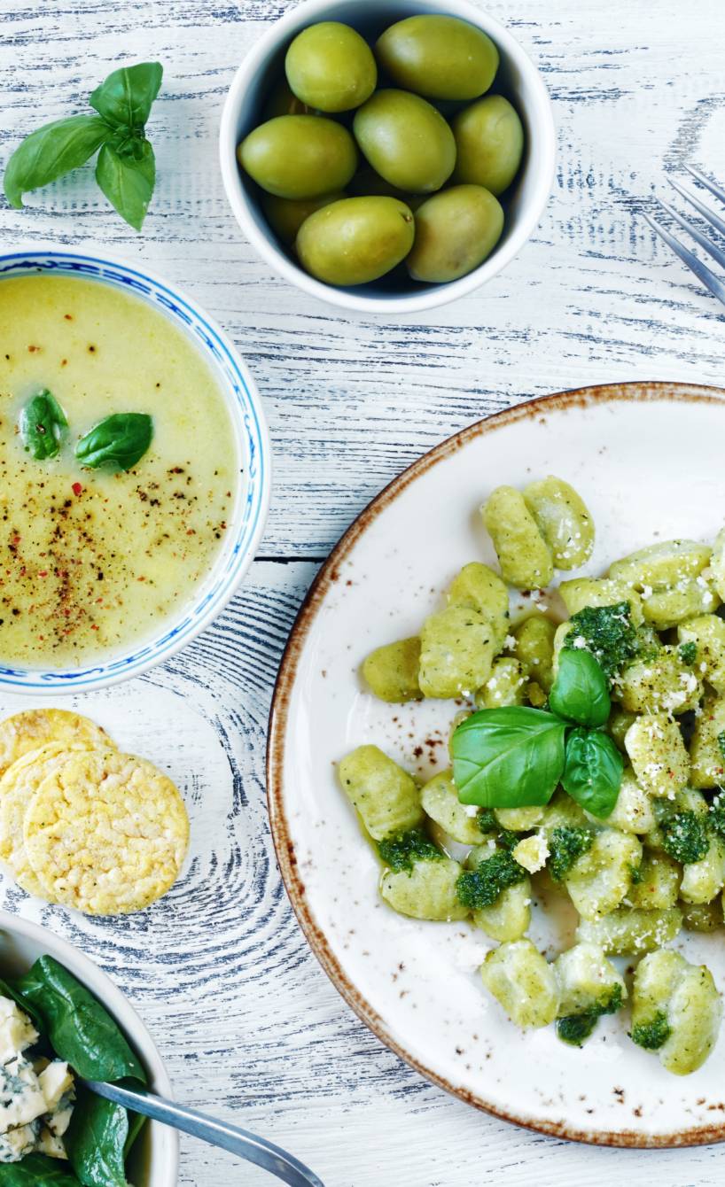 Gnocchi mit verschiedenen Beilagen wie grünem Spargel, Mozzarella und Oliven auf einem Tisch