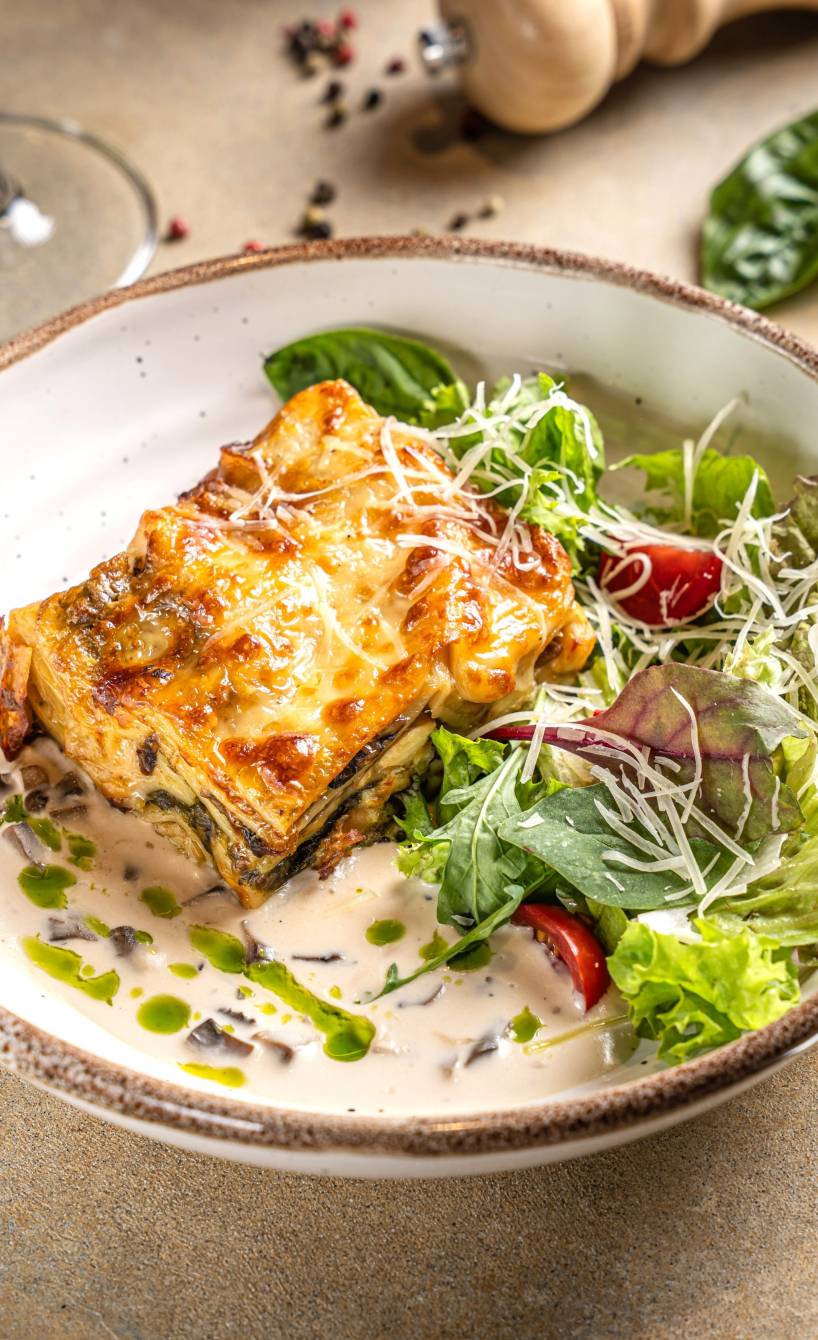 Ein Stück Lasagne angerichtet mit Salat auf einem Pastateller