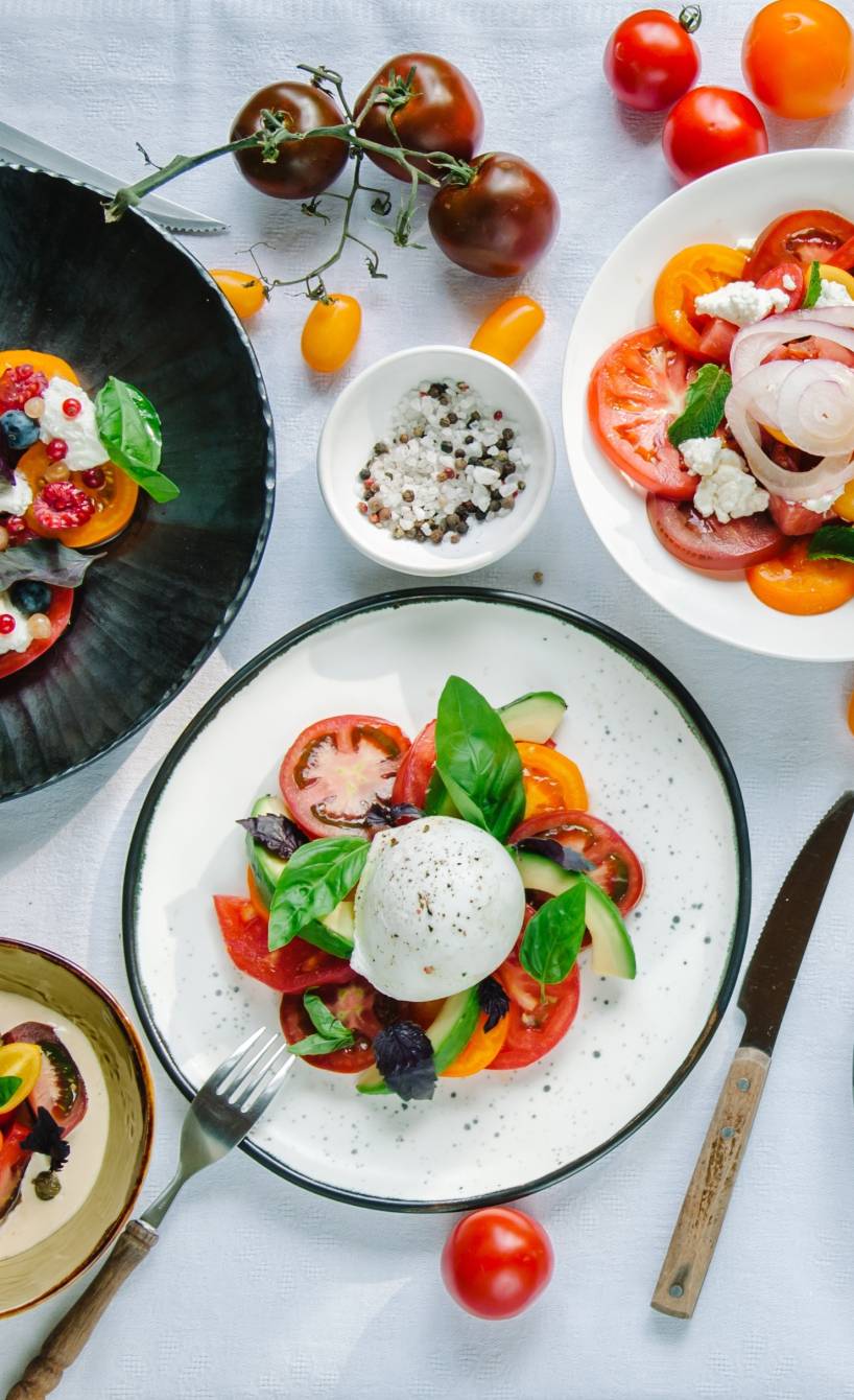 Verschiedene italienische Sommergerichte mit Tomaten und Burrata auf einem großen Gartentisch