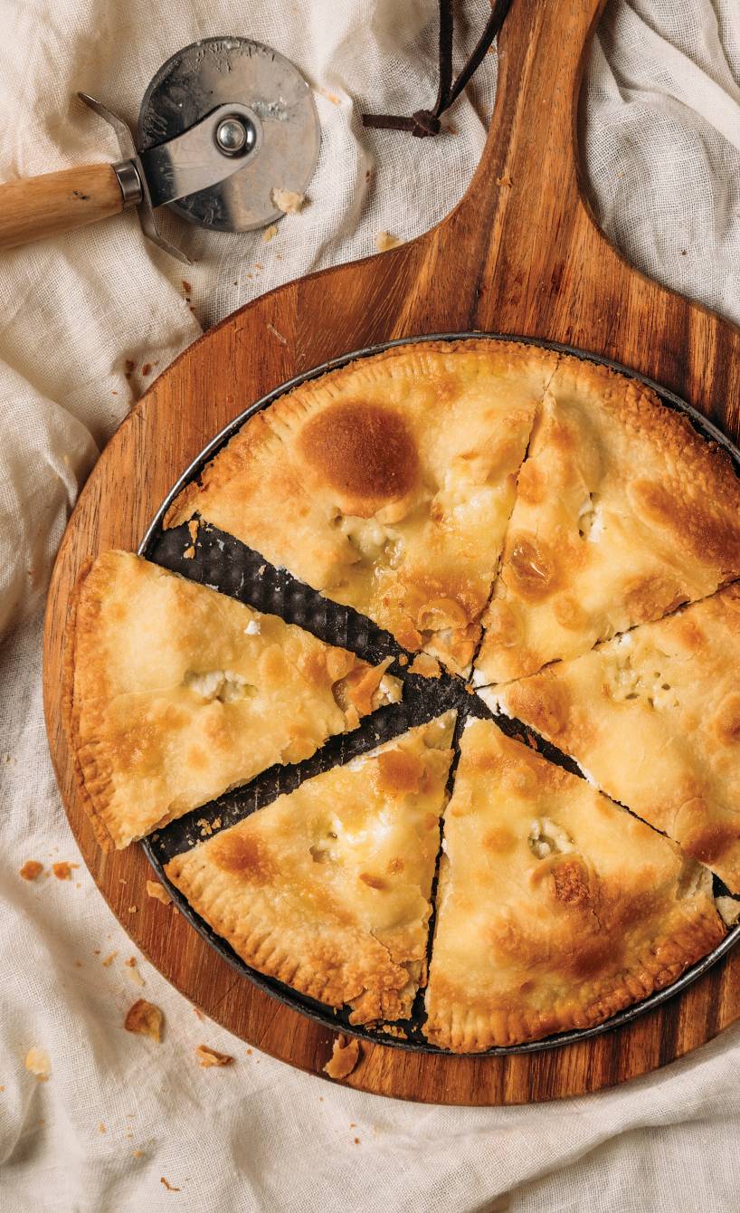 Runde Focaccia di Recco mit Käsefüllung angeschnitten auf einem Holzbrett