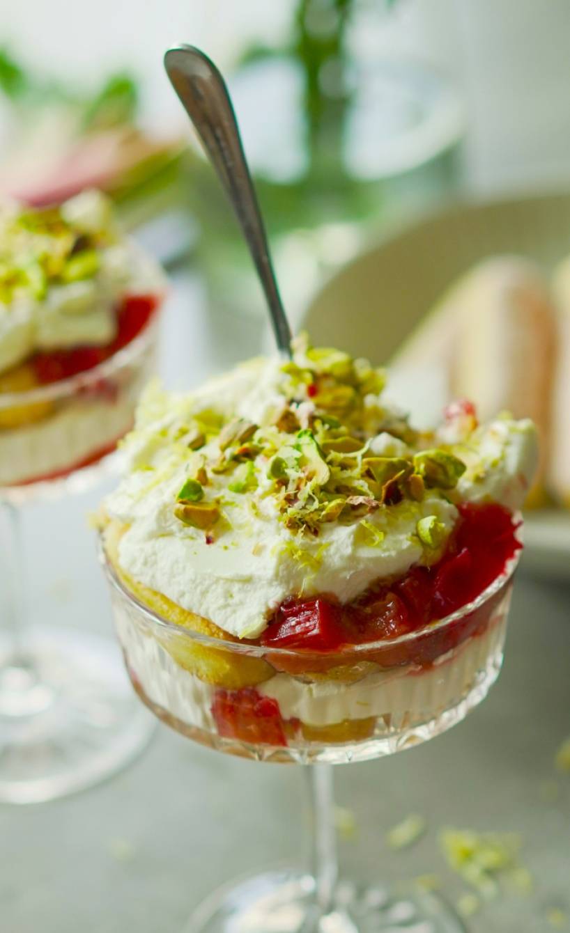 Rhabarber-Limoncello-Tiramisu in zwei Dessertgläser geschichtet getoppt von Pistazien auf einem Tisch