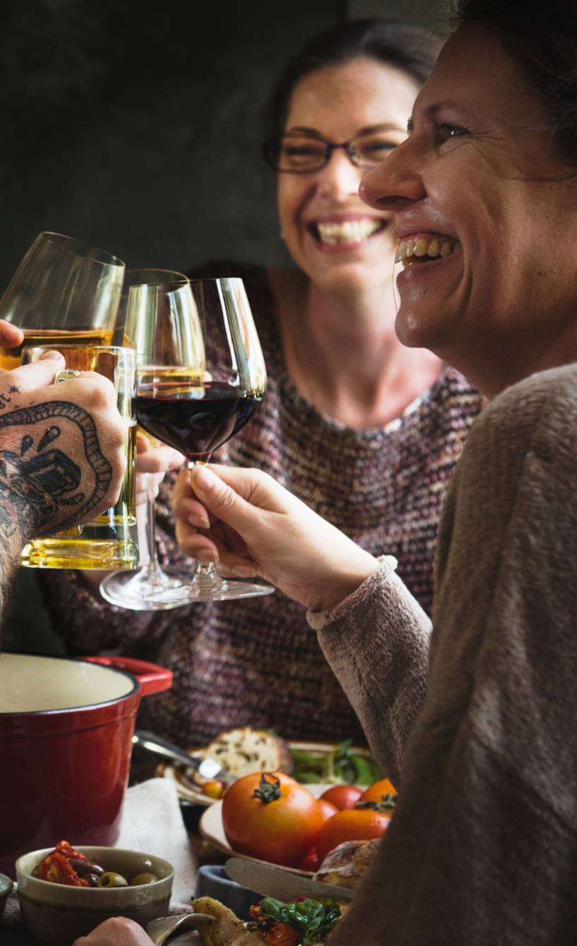 Vier Menschen sitzen bei einem italienischen Abendessen und stoßen mit unterschiedlichen Weinen an