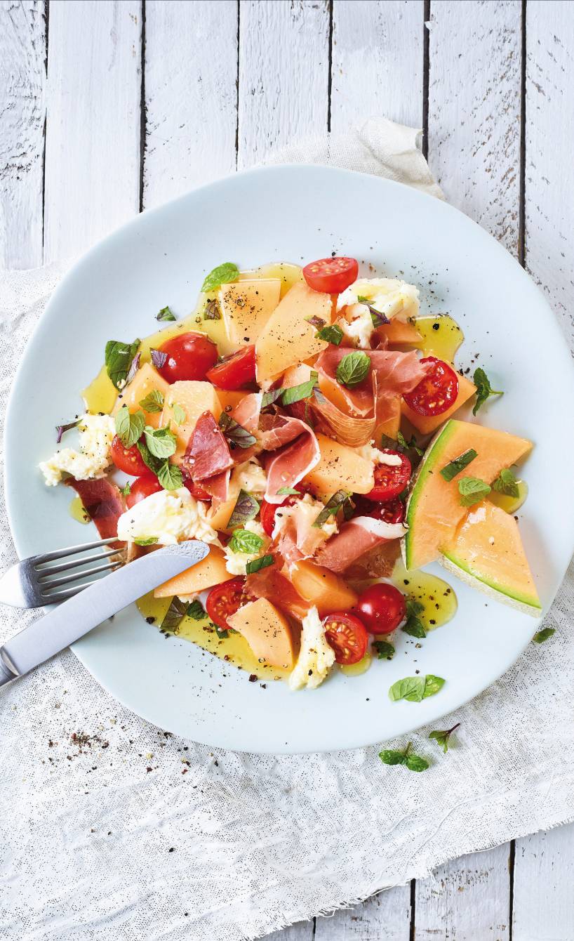 Melone-Mozzarella-Salat mit Schinken angerichtet auf einem Vorspeisenteller