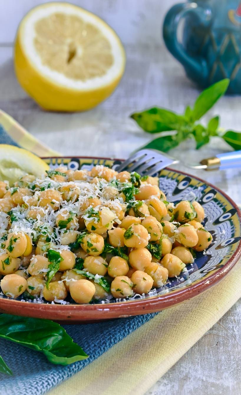 Kichererbsensalat mit Kräutern und Parmesan angerichtet mit frischer Zitrone auf einer Salatplatte