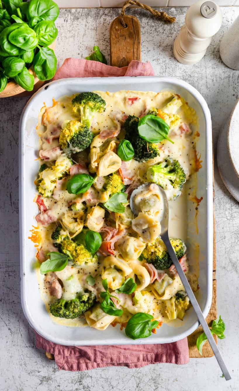 Gebackener Tortellini-Auflauf mit Brokkoli, Schinken und Sahnesauce in einer Auflaufform auf einem Tisch