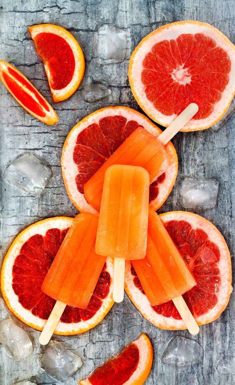Selbstgemachtes Aperol-Stieleis angerichtet auf Grapefruitscheiben von oben auf einem Tisch
