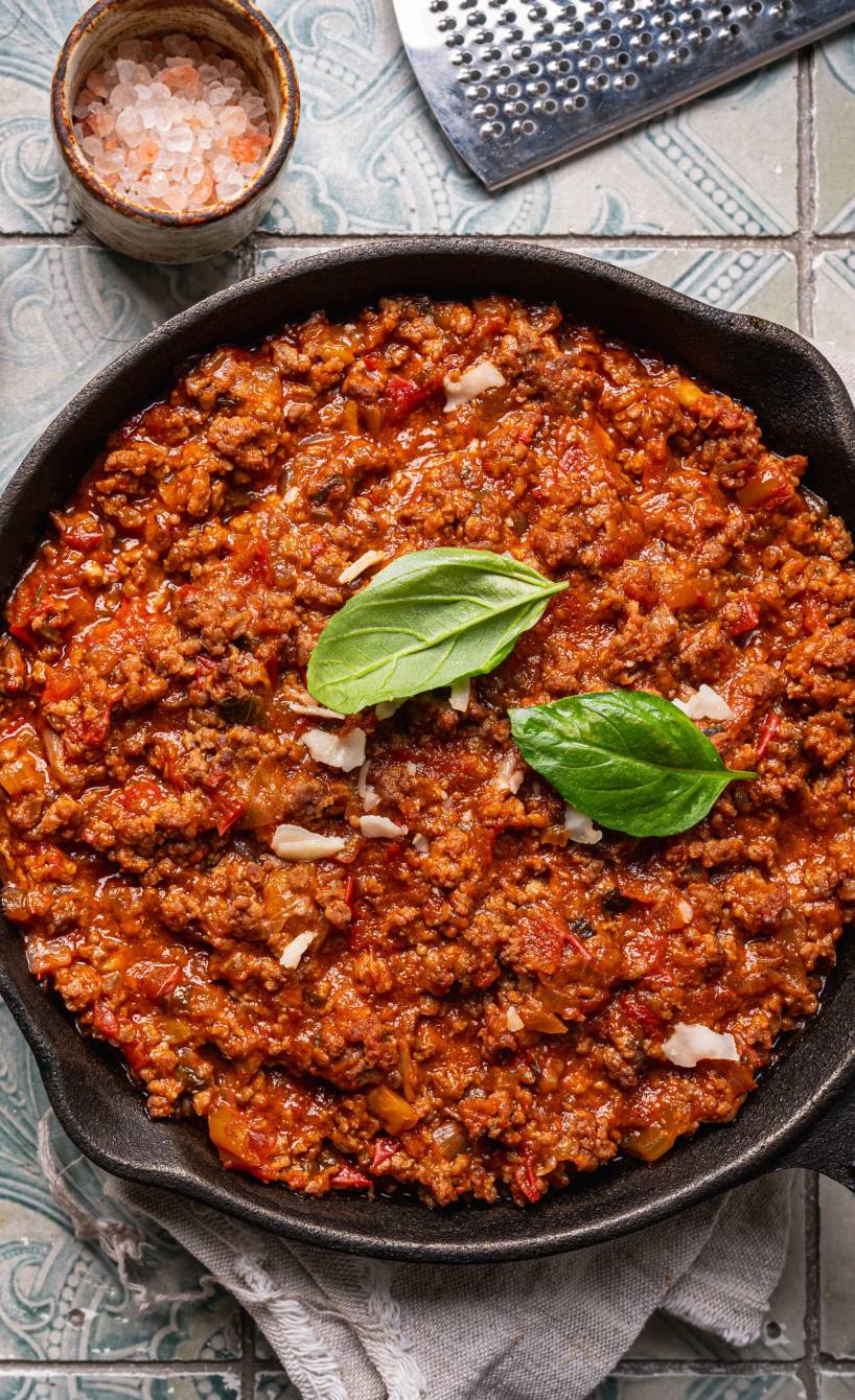 Slebstgekochte Bolognese in einer Pfanne auf einem Tisch umgeben von Zutaten
