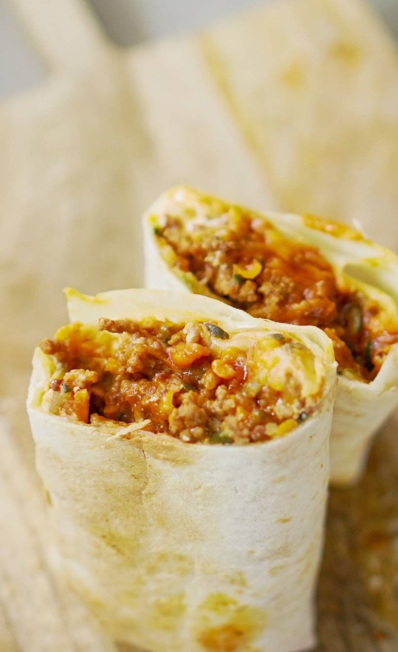 Halbierter „Bolognese-Style“ Wrap auf einem Holzbrett Halbierter „Bolognese-Style“ Wrap auf einem Holzbrett