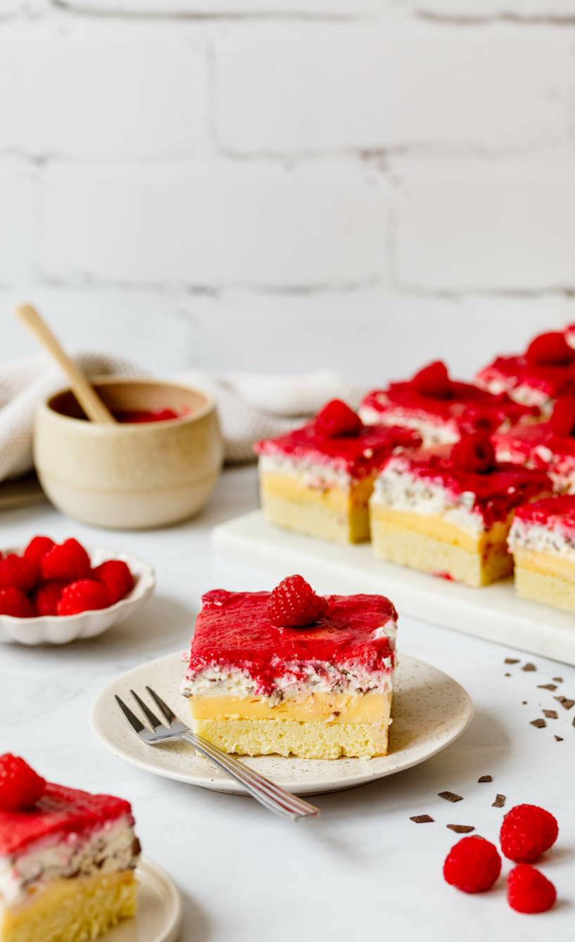 Ein Stück Himbeer-Stracciatella-Blechkuchen mit Pudding auf einem Kuchentelle