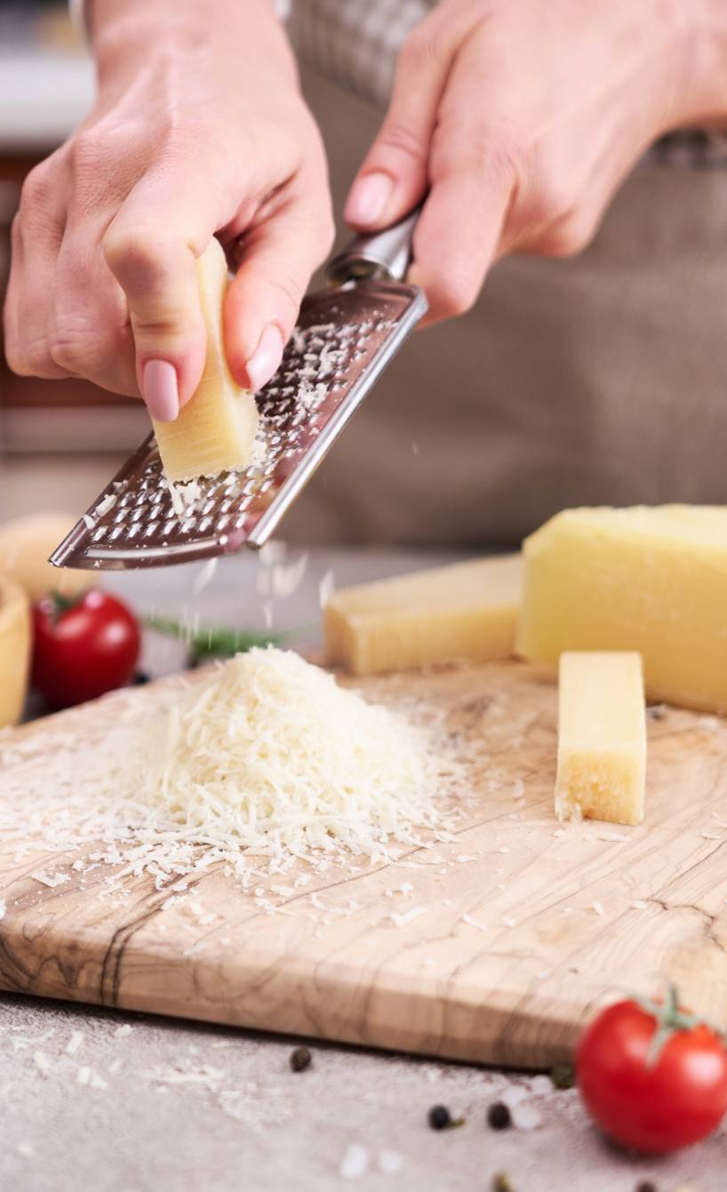 Eine Frau reibt Parmesan auf ein Holzbrett Eine Frau reibt Parmesan auf ein Holzbrett