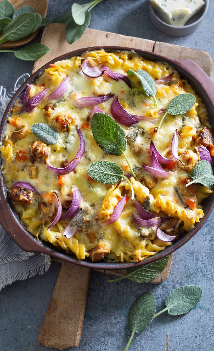 Überbackener Salsiccia-Pasta-Auflauf mit Gorgonzola und Birne angerichtet auf einem Tisch mit Salbeiblättern