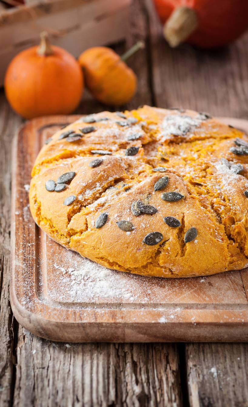 Selbstgebackenes Hokkaido Kürbisbrot auf einem bemehlten Holzbrett