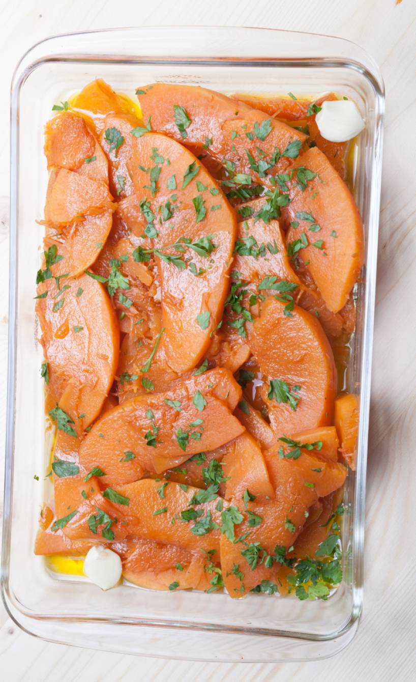 Zucca in agrodolce Kürbisspalten süß sauer in einer Glasschale garniert mit Petersilie auf einem Tisch