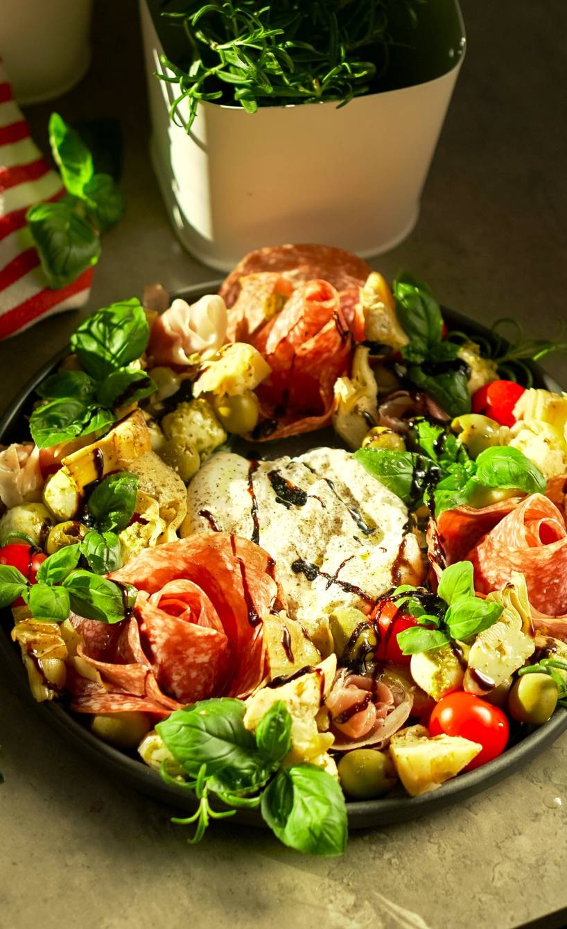 Selbstgemachter Antipasti-Kranz mit Burrata und Salami-Rosen auf einem Tisch