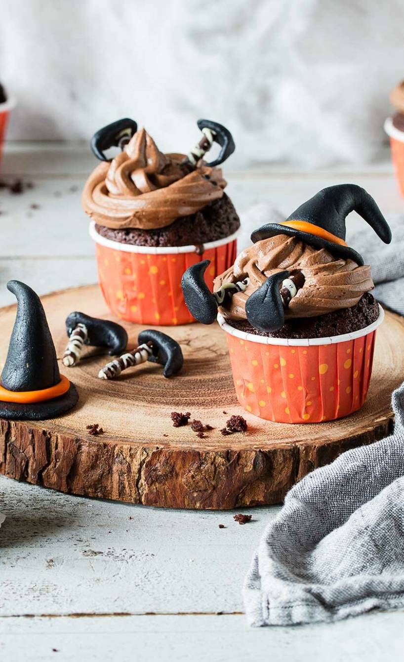 Selbstgebackene Hexen-Cupcakes auf einem für Halloween dekorierten Tisch