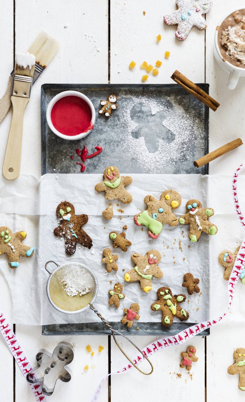 Selbstgebackene Lebkuchenmännchen auf einem Backblech verziert mit bunten Gesichtern