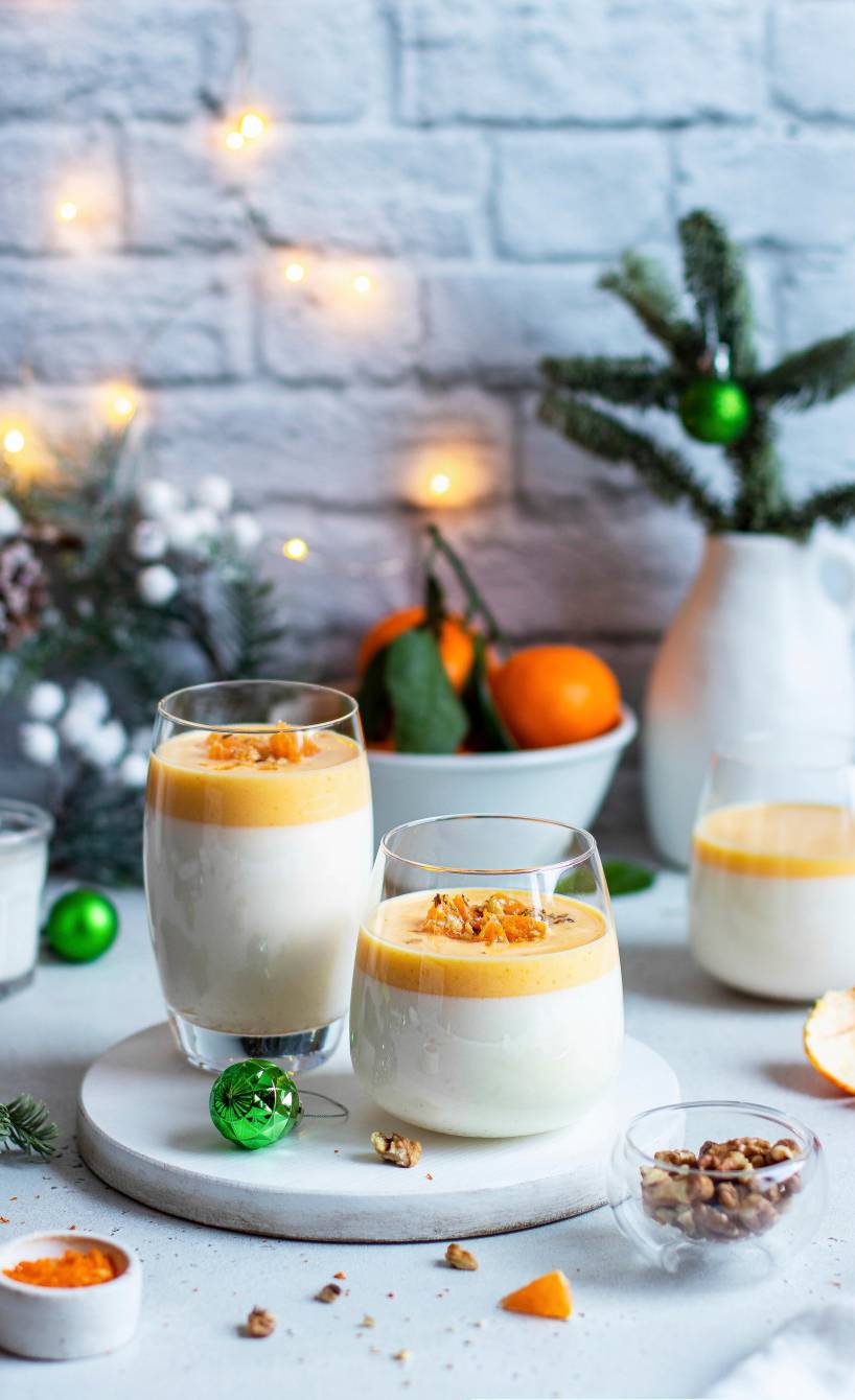 Mandarinen-Panna-cotta geschichtet in mehrere Dessertgläser auf einem weihnachtlich dekorierten Tisch
