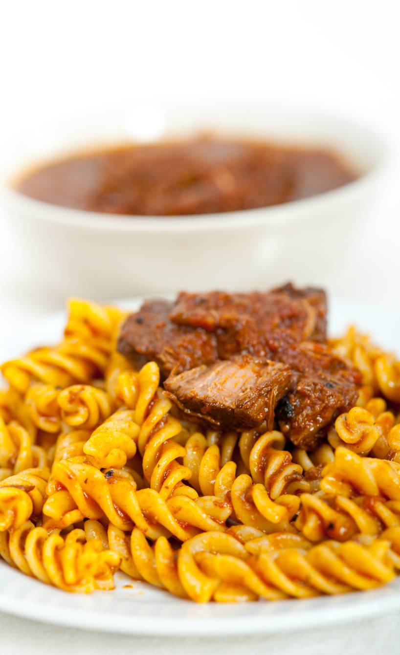 Ragù napoletano Schmorfleisch mit Sauce angerichtet auf Fusilli auf einem tiefen Teller