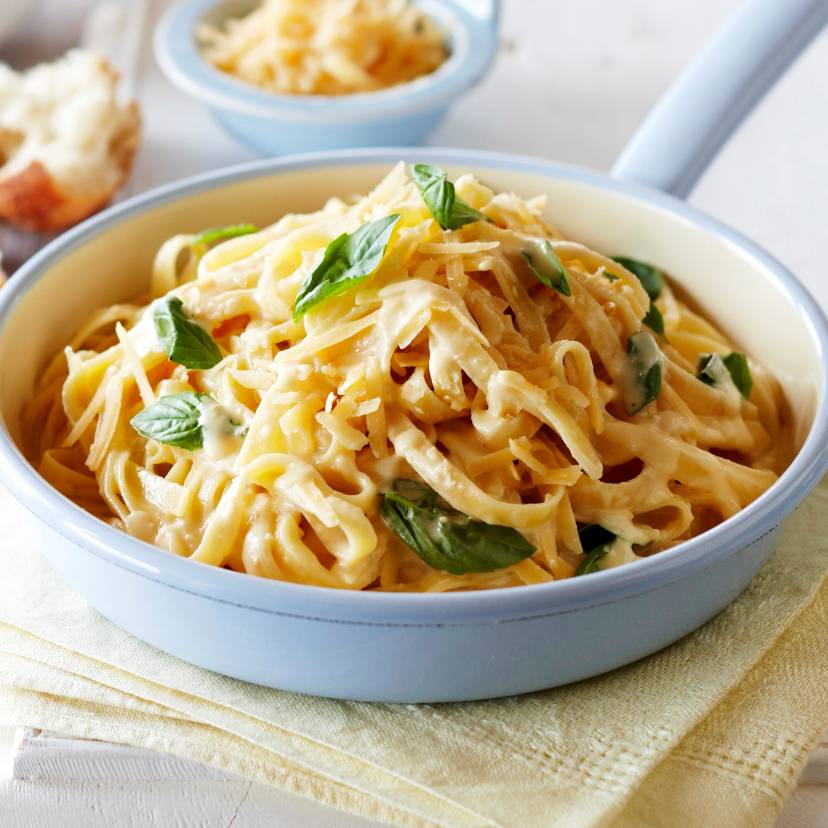 Pasta Alfredo in einer Stielpfanne getoppt mit Käse und frischem Basilikum