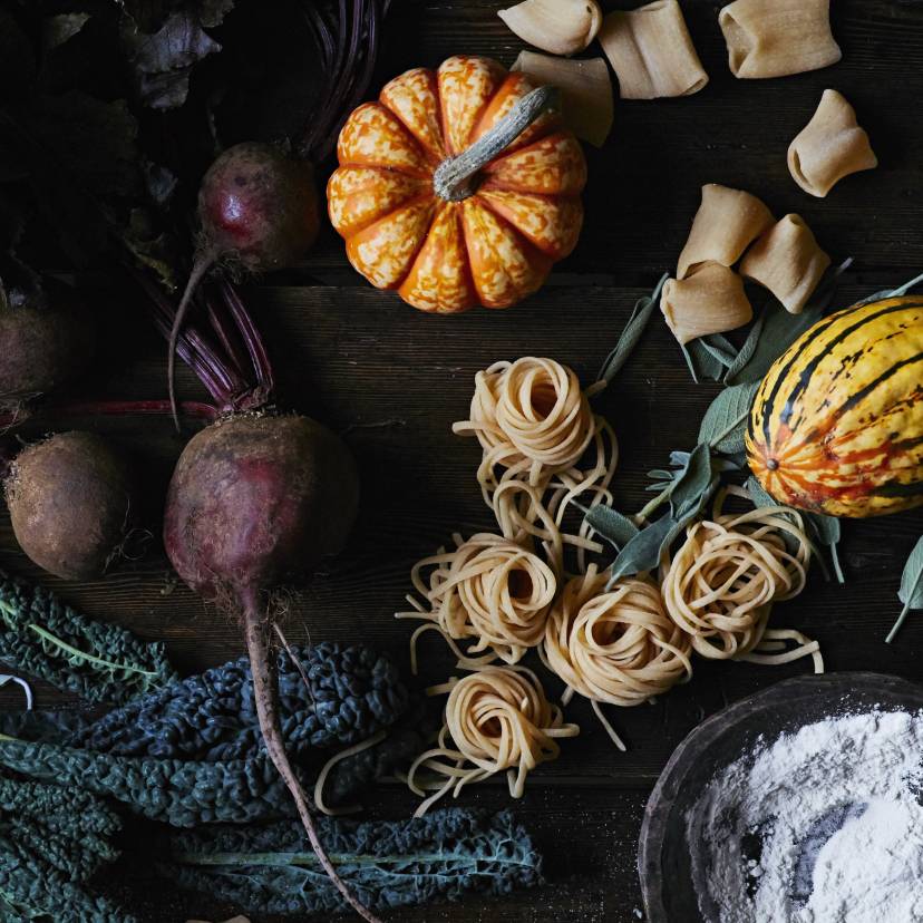 Saisonale Zutaten für den Herbst sowie andere für gesunde italienische Gerichte auf einem Holztisch