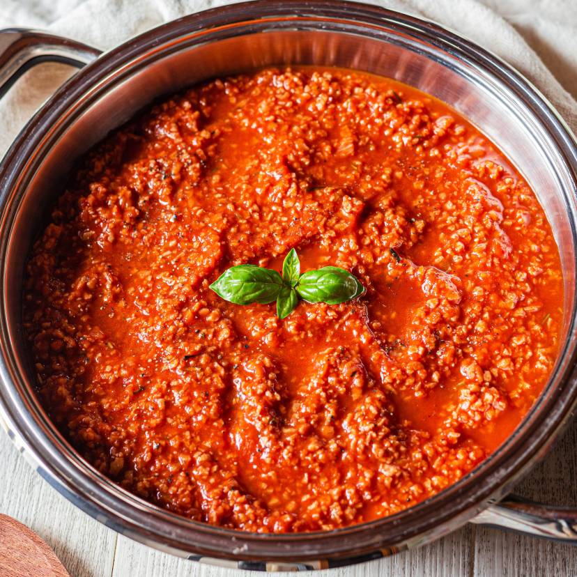 Bolognese Soße in einem Topf garniert mit frischem Basilikum auf einem Küchentisch
