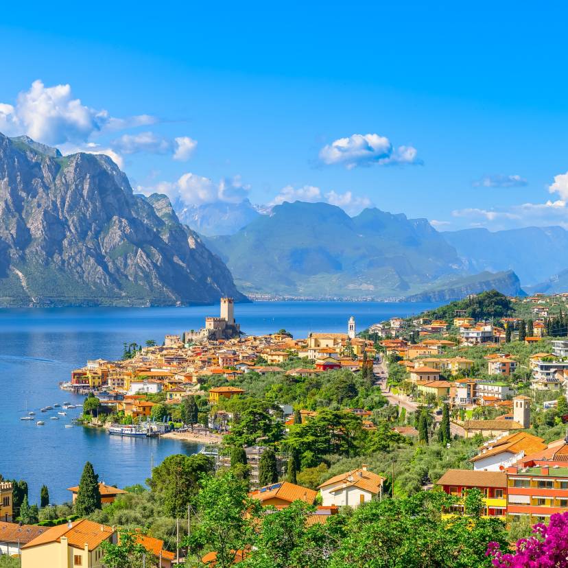 Blick über die Stadt Malescine, den Gardasee, blühende Bäume und Berge