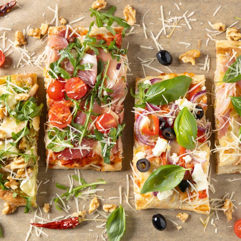 Vier verschieden belegte, angeschnittene Pinsen auf einem Tisch von oben