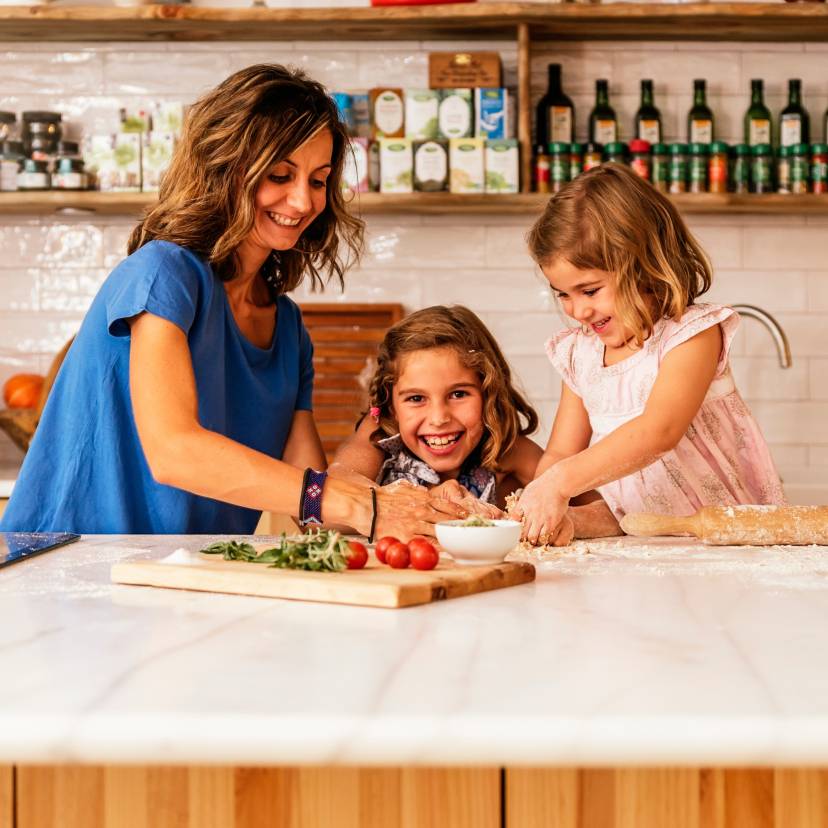 Eine Mutter backt in der Küche Pizza mit ihren zwei Töchtern