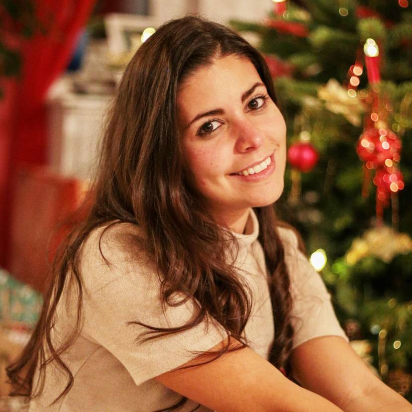 Serena Loddo vor einem geschmückten Weihnachtsbaum umgeben von Geschenken